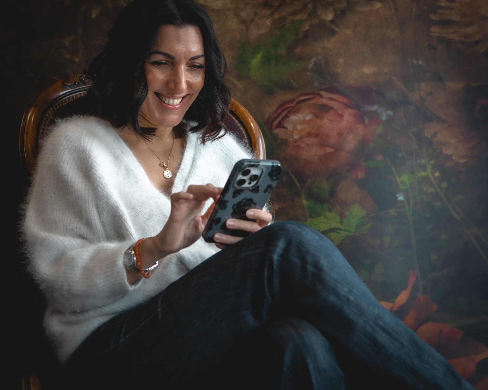 Naomi Buff smiling while using her phone in a comfortable chair